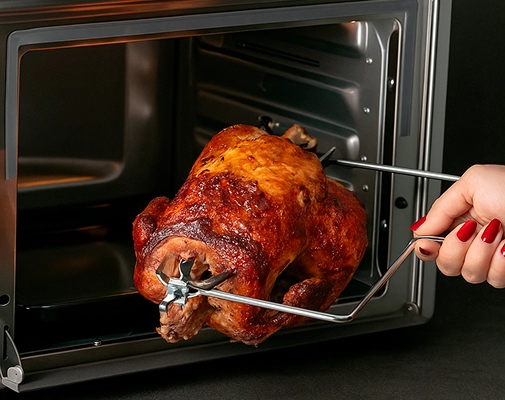 Imagem ilustrativa de um frango sendo colocado no forno fryer